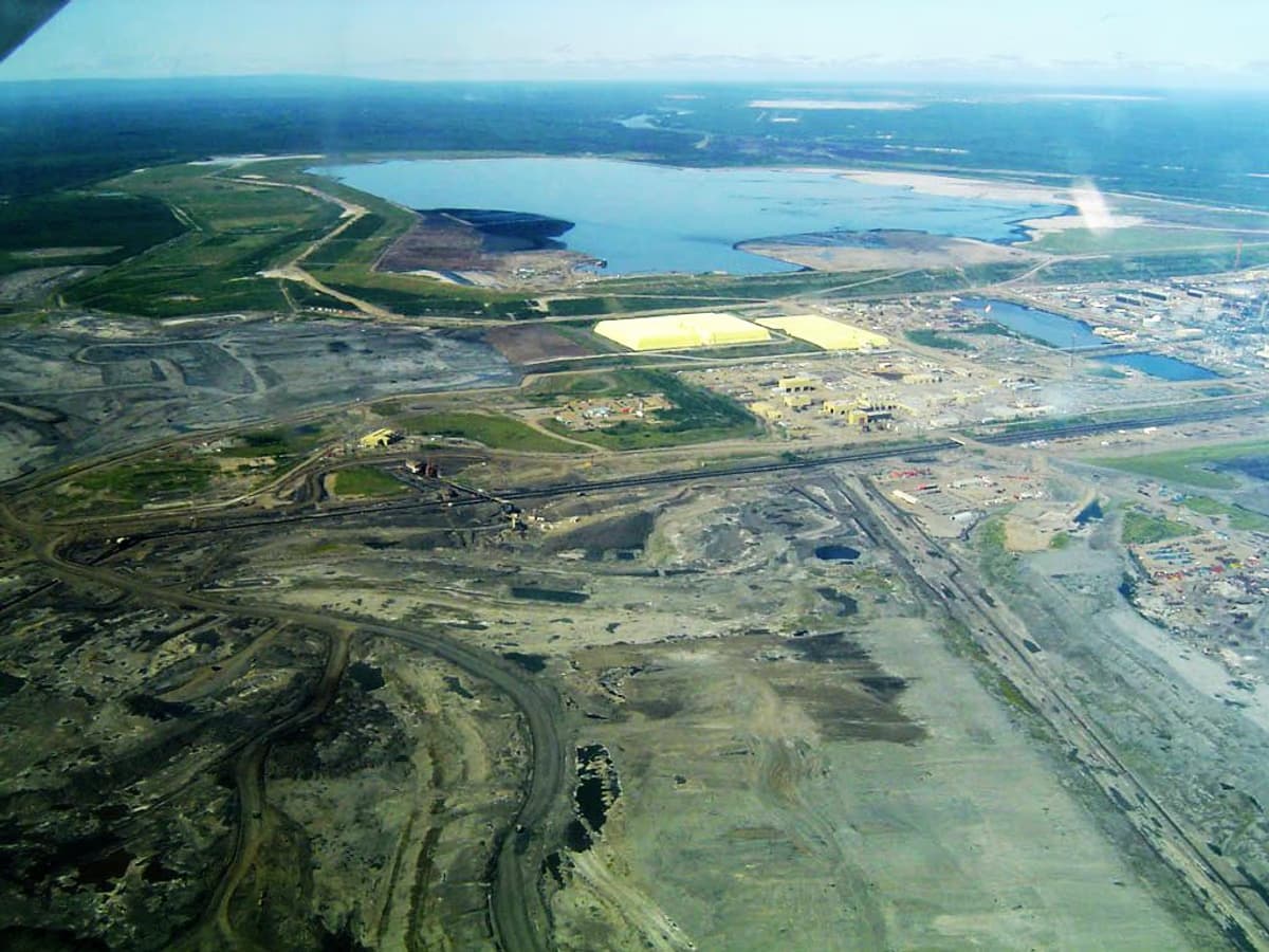 Aerial view of Syncrude oil sands mining operations with sulfur piles and tailings pond near Fort McMurray Alberta