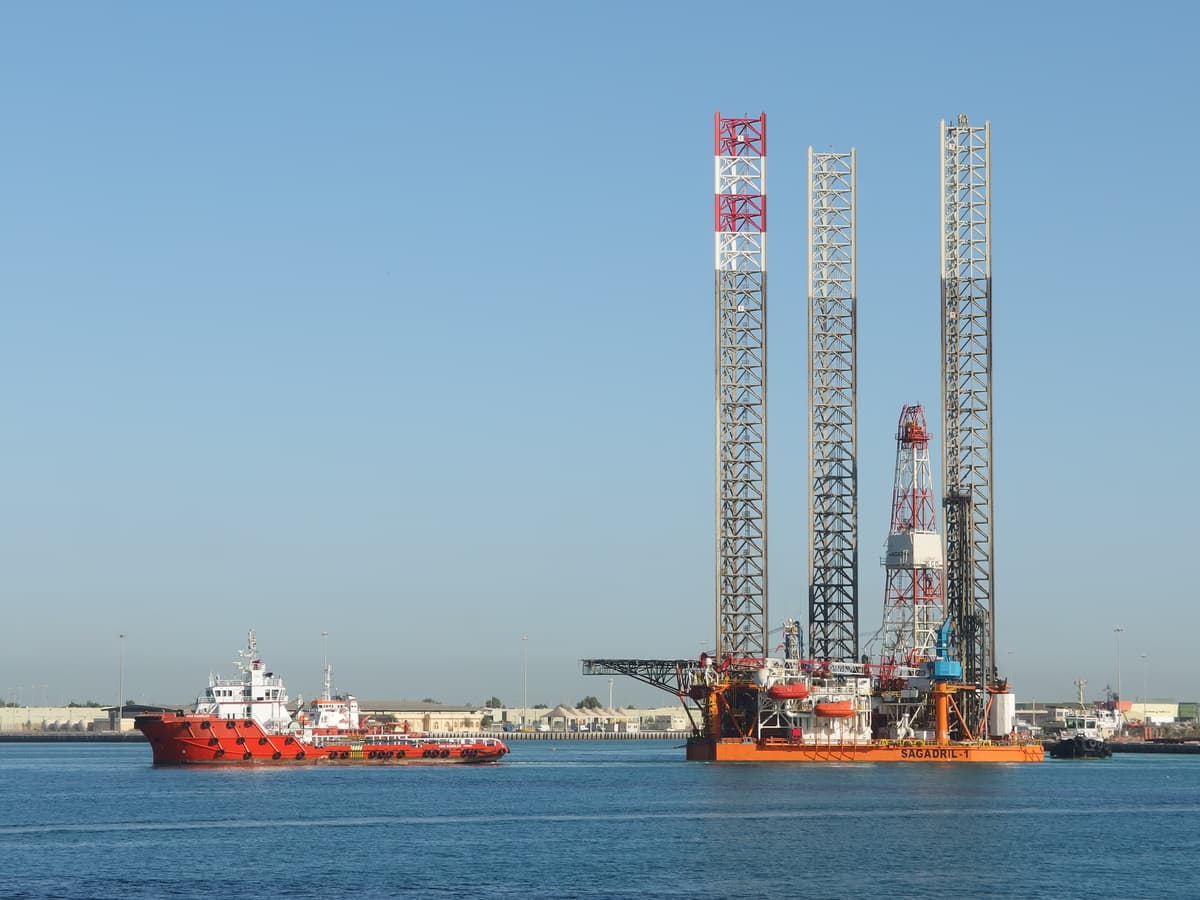 Offshore drilling rig positioned at the Abu Dhabi Corniche waterfront with an offshore supply vessel alongside