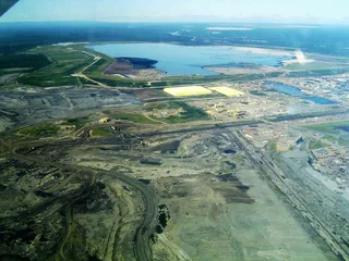 Aerial view of Syncrude oil sands mining operations with sulfur piles and tailings pond near Fort McMurray Alberta