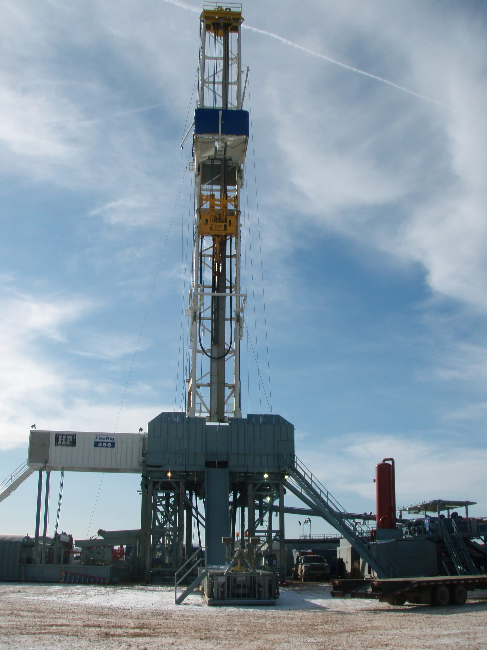 Onshore drilling rig mast and equipment standing at a land well site in the United States