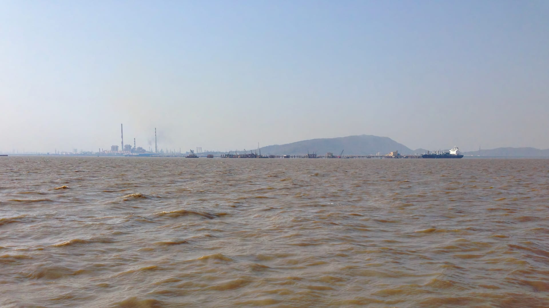 Mumbai oil refinery viewed from Bombay Harbor with oil tanker approaching facility
