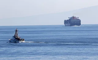 US Coast Guard cutter transiting the Strait of Hormuz with container ship in background