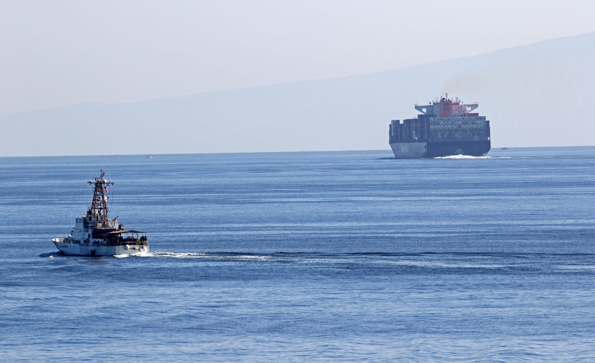 US Coast Guard cutter transiting the Strait of Hormuz with container ship in background
