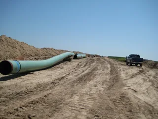 Stacked 30-inch diameter steel pipeline segments staged in a yard for Keystone crude oil pipeline construction in the United States