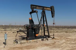 Oil pump jack operating in the Permian Basin under a clear blue sky