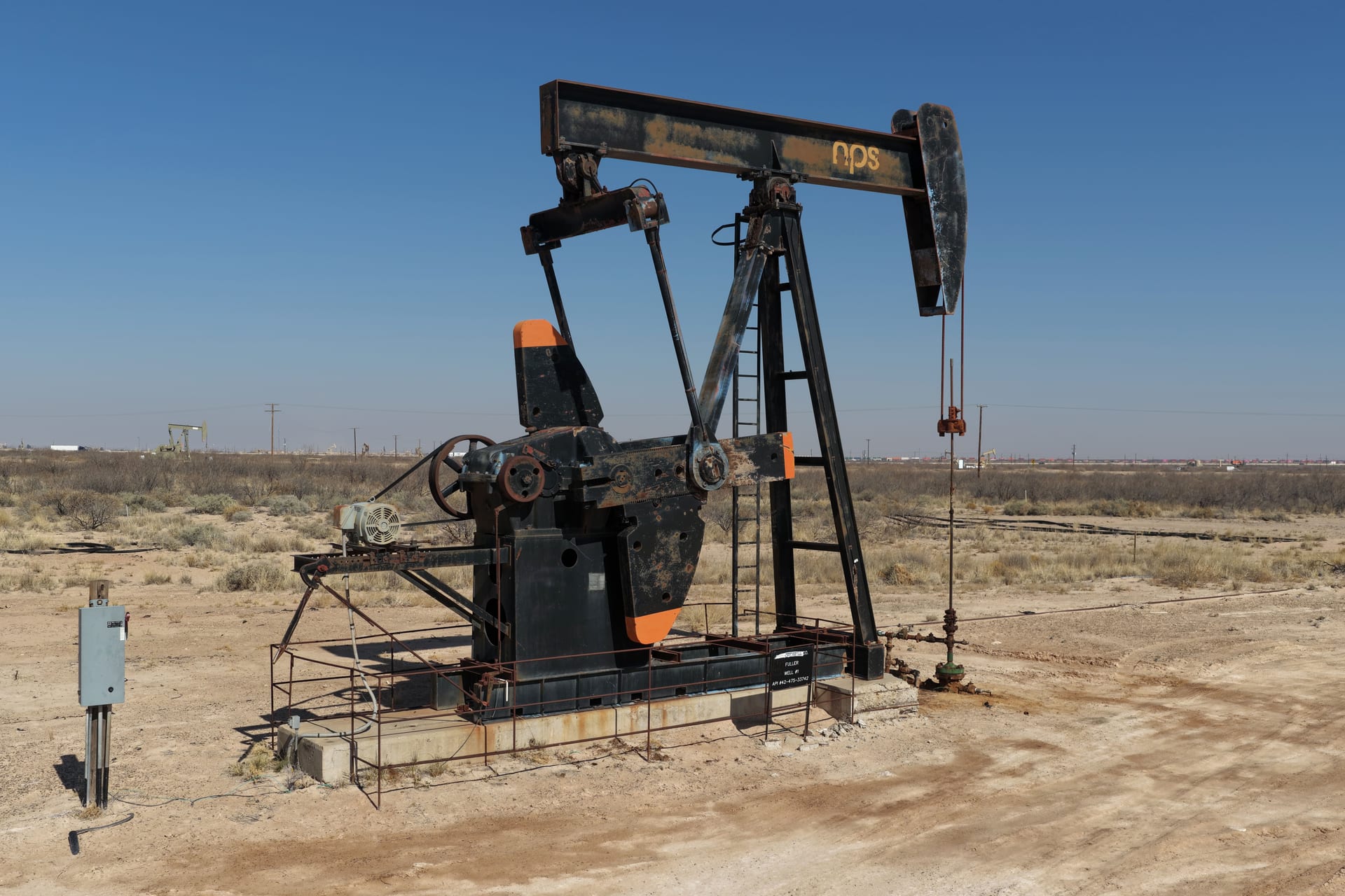 Oil pump jack operating in the Permian Basin under a clear blue sky