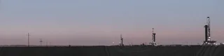Devon Energy drilling rigs at a Permian Basin multi-well production pad