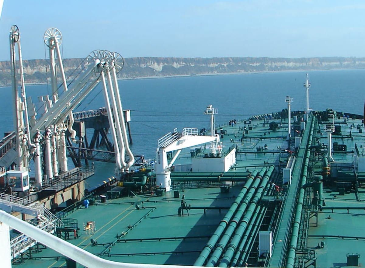 VLCC crude oil tanker discharging at port terminal via Chicksan transfer arms