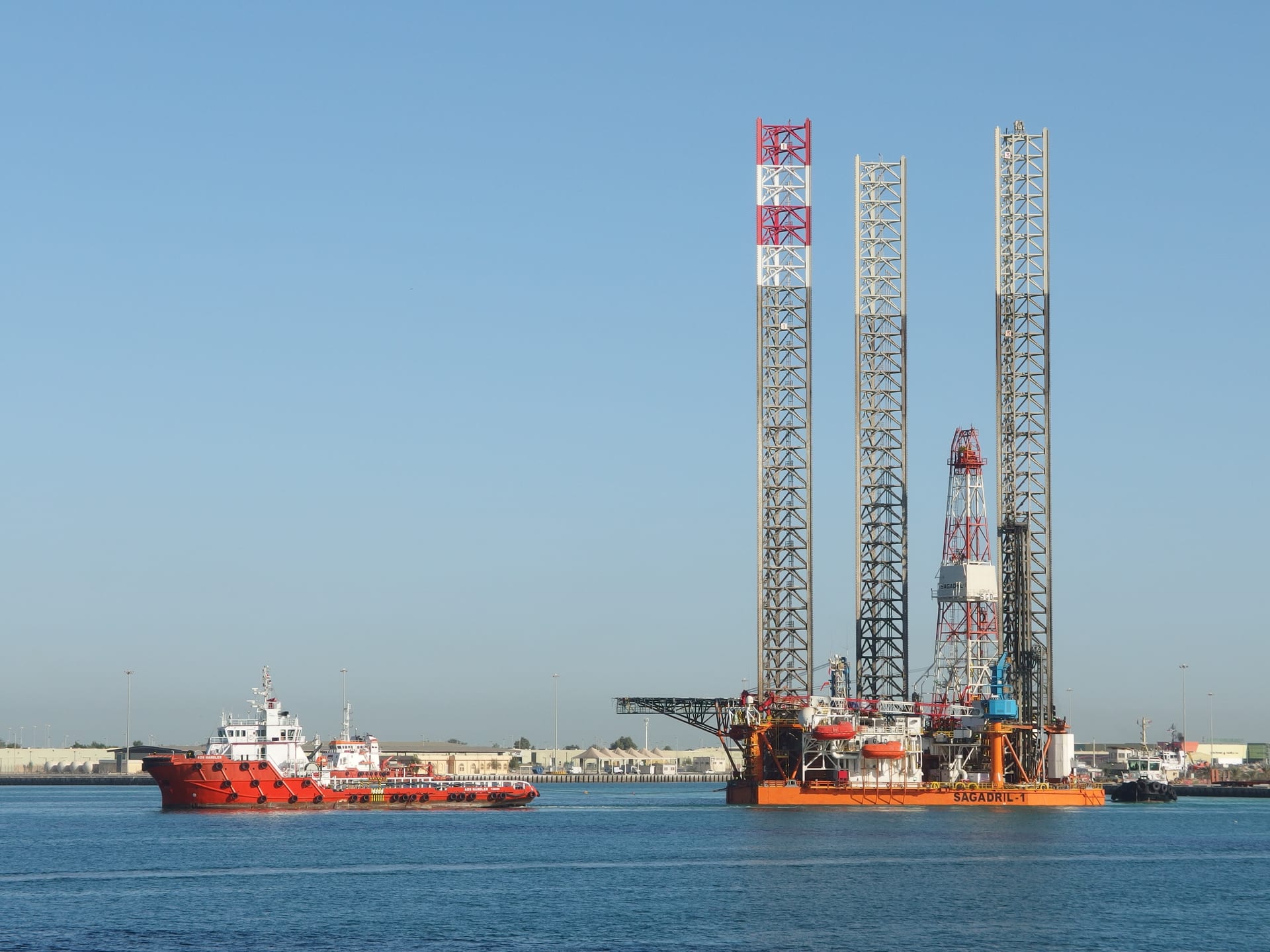 Offshore drilling rig positioned at the Abu Dhabi Corniche waterfront with an offshore supply vessel alongside