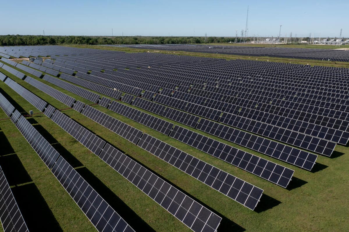 TotalEnergies solar farm with rows of photovoltaic panels under partly cloudy European sky daytime view